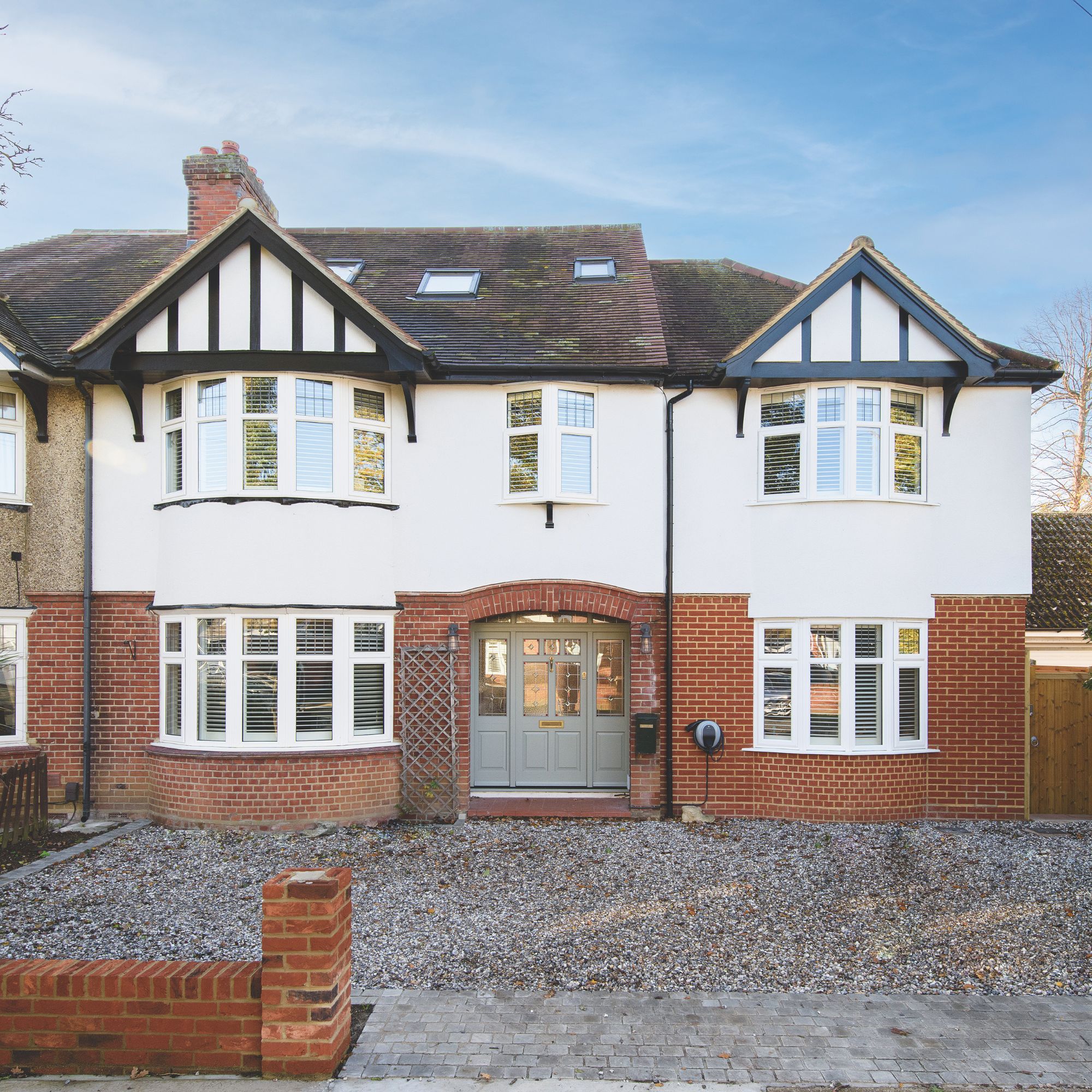 Traditional home exterior, with brick and render facade, white windows and large entrance