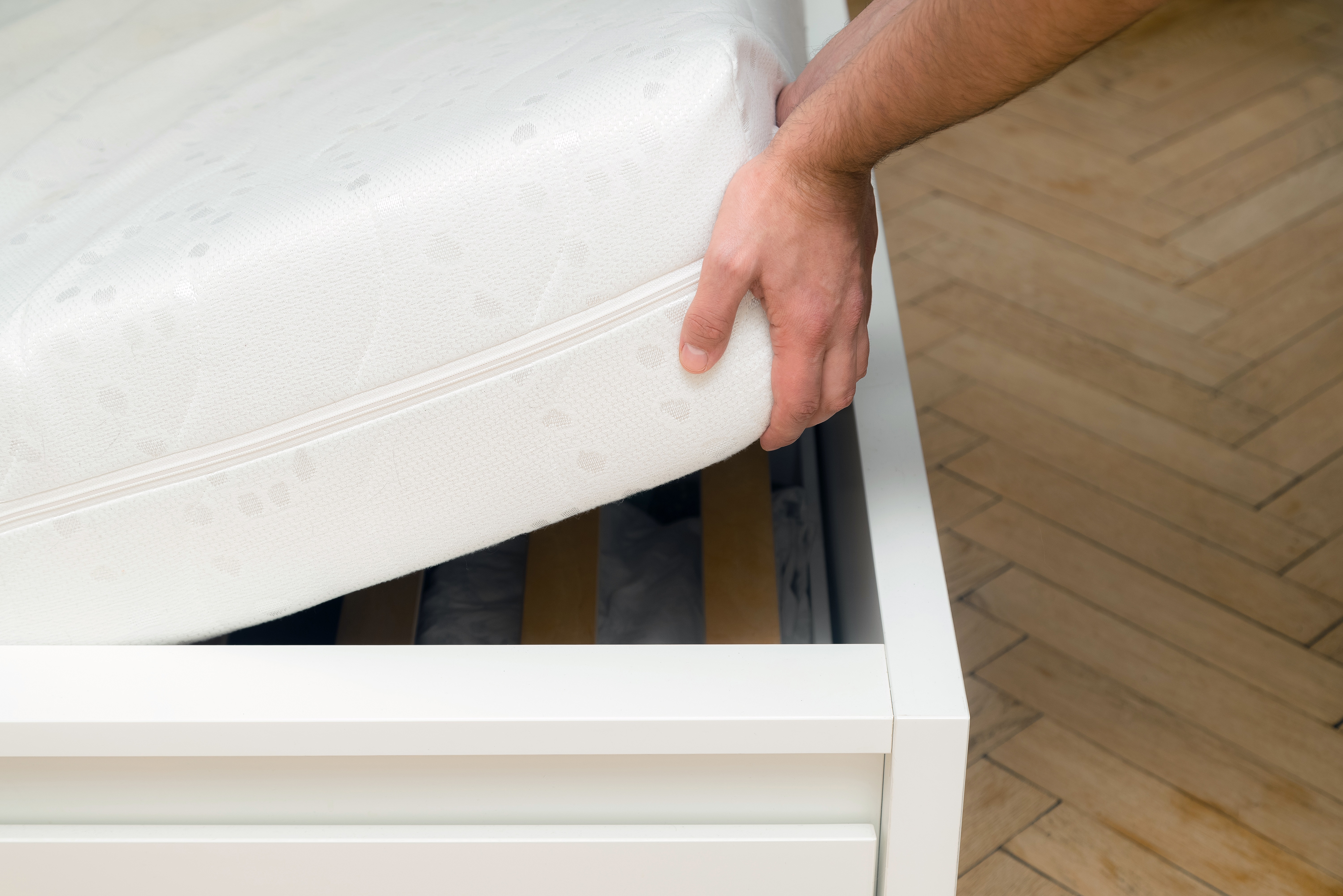 A person putting a mattress on a bed frame