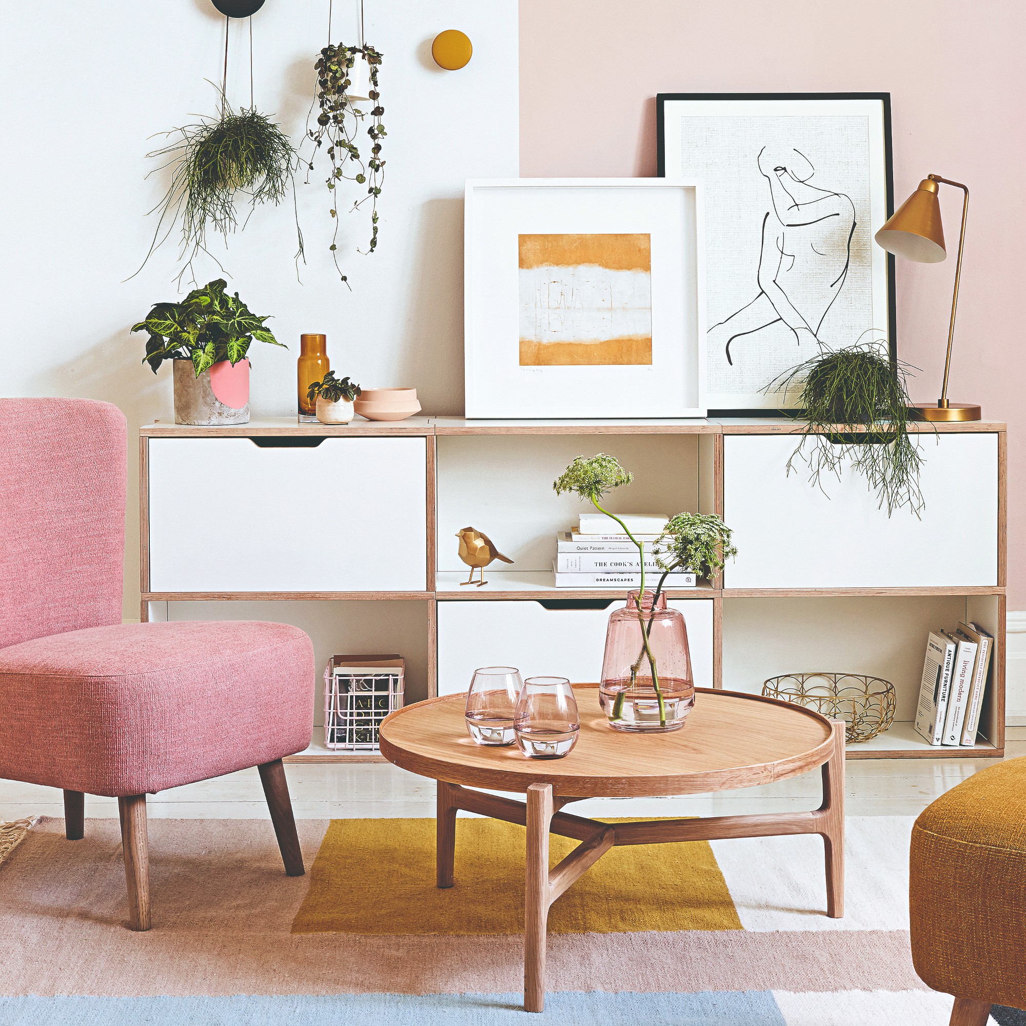 A living room with a pink chair and colour-blocked rug