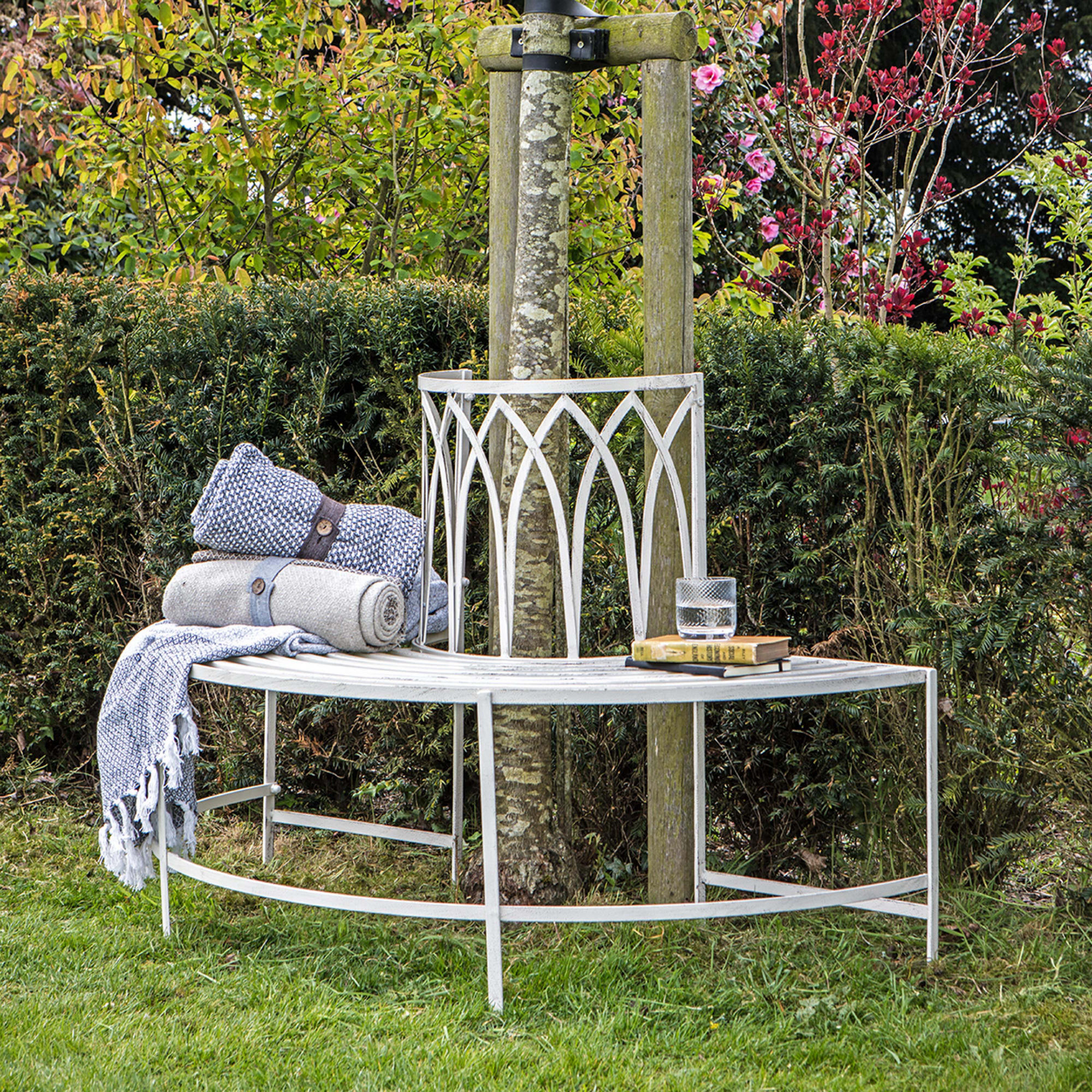 metal garden bench around tree, blankets, books