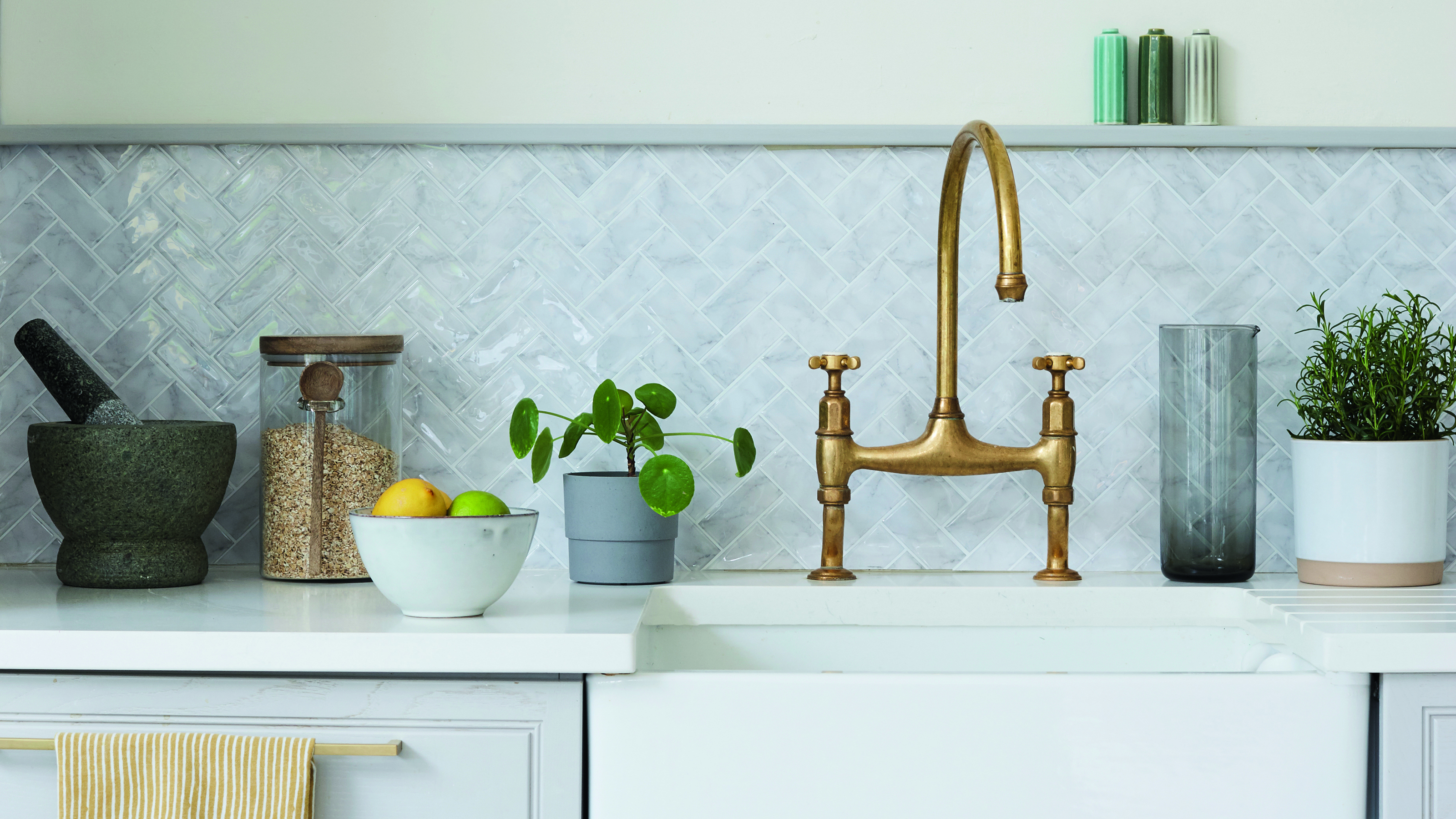 Grey kitchen with white worktop, grey mosaic tiled splashback and a belfast sink with brass vintage tap