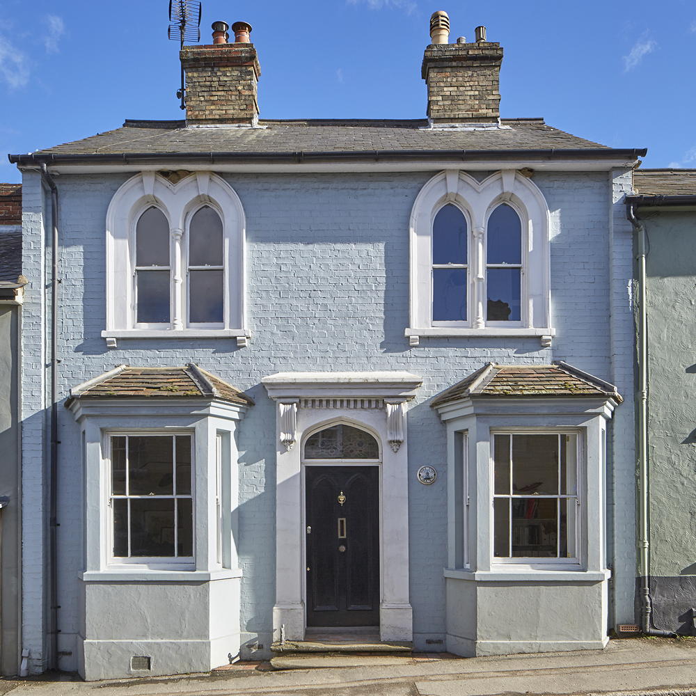 Blue-grey house with two chimneys, wooden door and charcoal roof