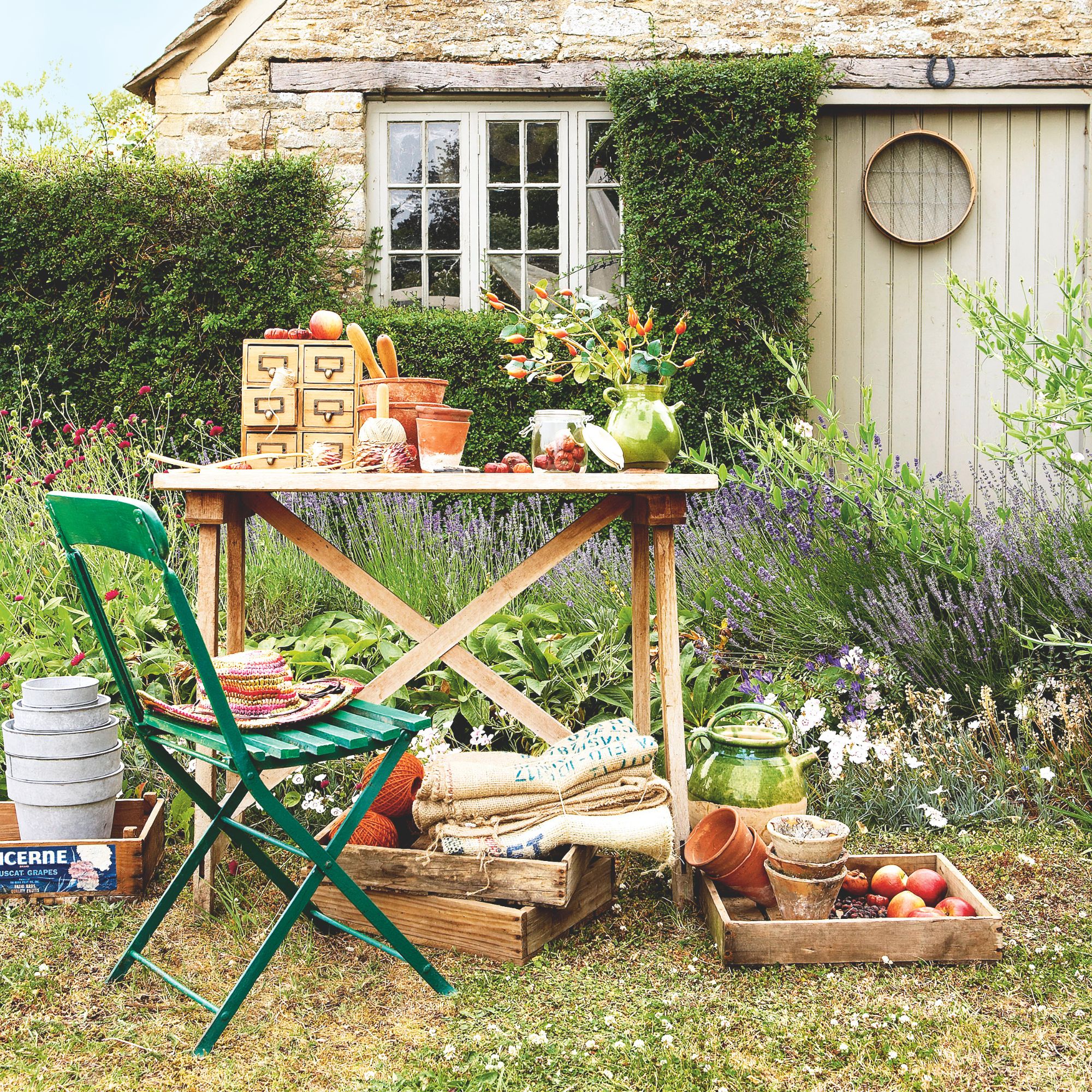Green garden chair next to wooden potting table with plant pots and garden string